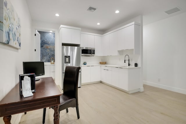 kitchen with white cabinetry, appliances with stainless steel finishes, sink, and light wood-type flooring