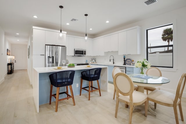 kitchen with white cabinets, stainless steel appliances, sink, and pendant lighting