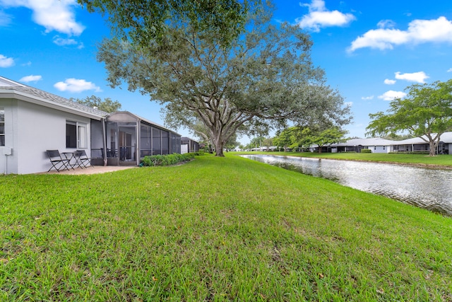 view of yard featuring a patio, a water view, and glass enclosure