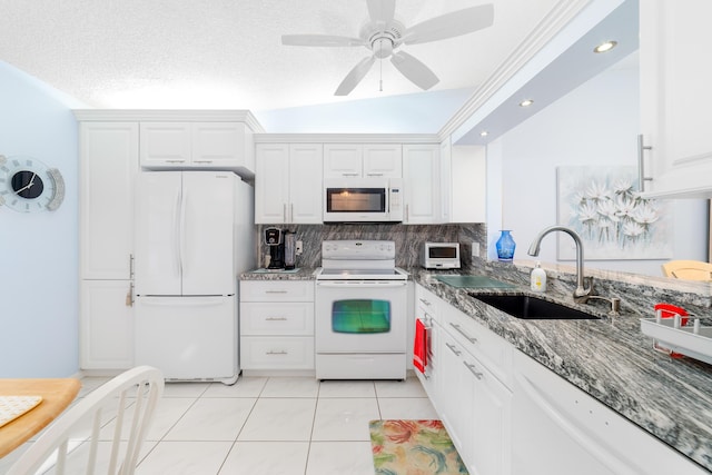 kitchen featuring sink, dark stone countertops, white cabinets, light tile patterned floors, and white appliances