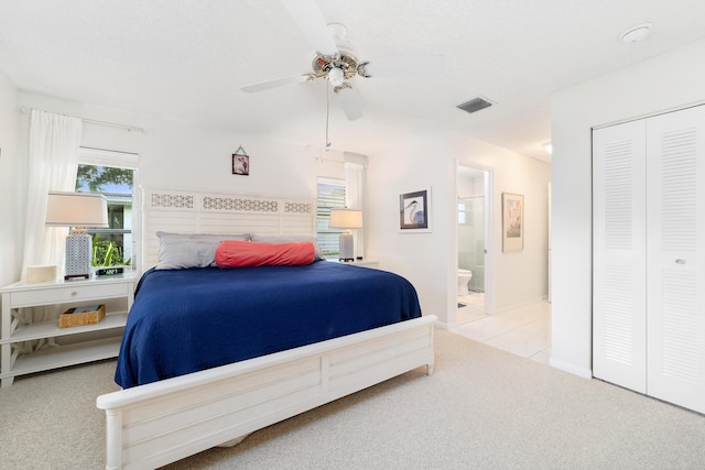 bedroom featuring ceiling fan, light colored carpet, ensuite bath, and a closet