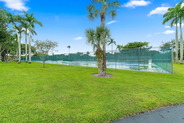 exterior space featuring tennis court, a lawn, and a water view