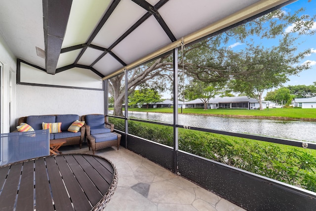 sunroom / solarium featuring a water view and lofted ceiling