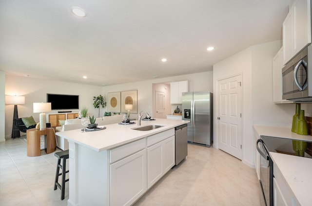 kitchen with stainless steel appliances, a kitchen island with sink, white cabinets, sink, and a kitchen bar