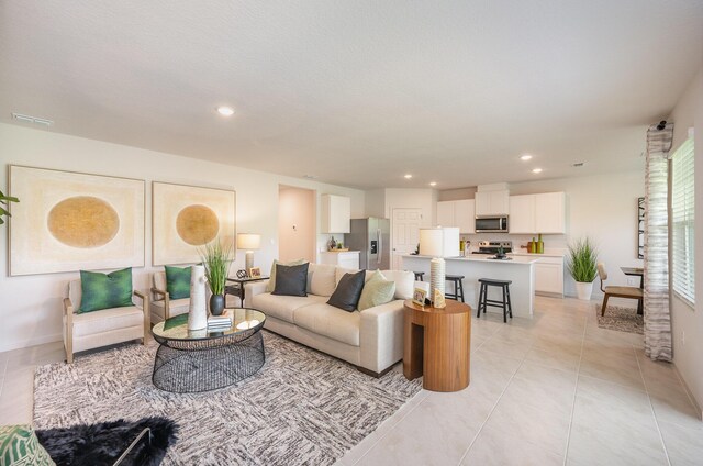 kitchen with a kitchen island with sink, stainless steel appliances, sink, white cabinets, and light stone counters