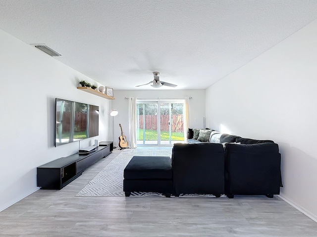 living room featuring a textured ceiling, hardwood / wood-style flooring, and ceiling fan