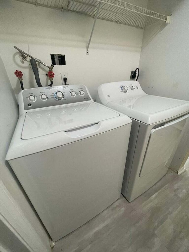 laundry area with washing machine and clothes dryer and hardwood / wood-style flooring