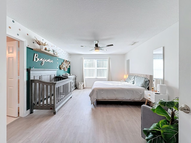 bedroom featuring a textured ceiling, light wood-type flooring, and ceiling fan