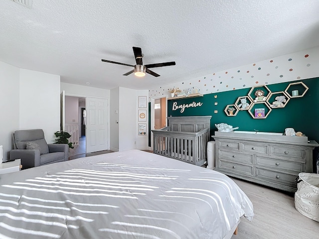 bedroom with a textured ceiling, ceiling fan, and light hardwood / wood-style flooring