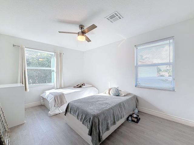 bedroom featuring a textured ceiling, light hardwood / wood-style flooring, and ceiling fan