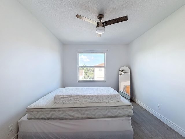 bedroom with a textured ceiling, ceiling fan, and dark hardwood / wood-style floors