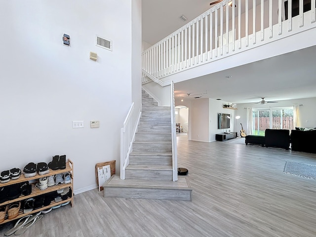 stairway featuring hardwood / wood-style floors, a high ceiling, and ceiling fan