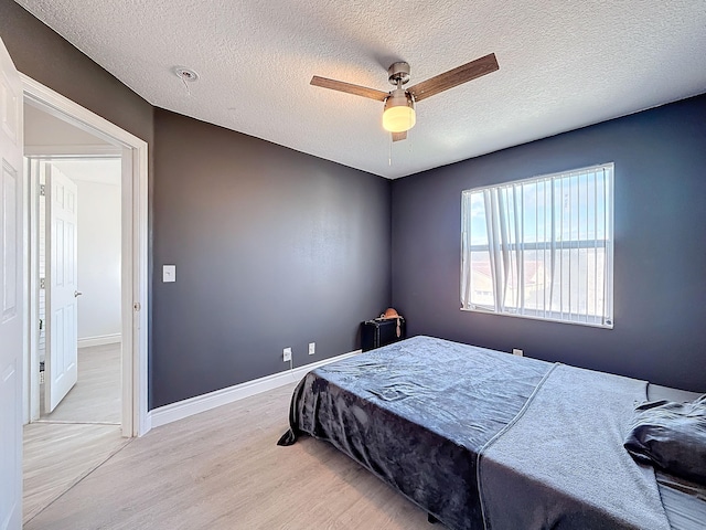 bedroom featuring a textured ceiling, ceiling fan, and light hardwood / wood-style flooring