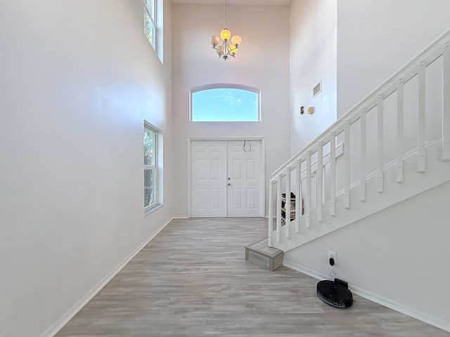 entrance foyer with light wood-type flooring, a chandelier, and a high ceiling