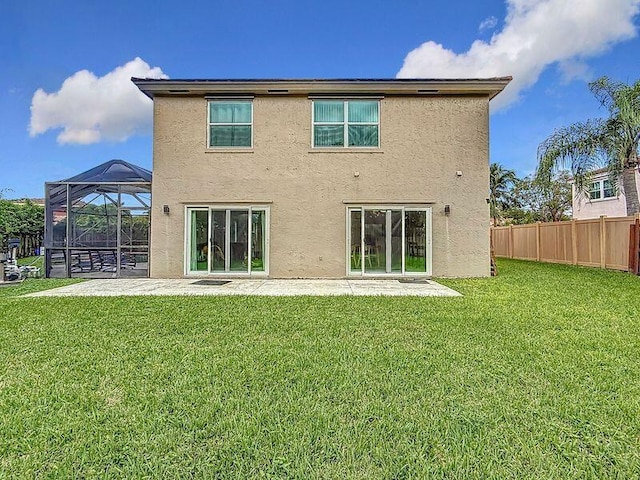 back of house with glass enclosure, a patio area, and a yard