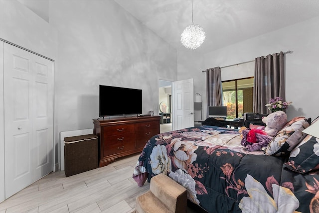 bedroom with an inviting chandelier, a closet, light hardwood / wood-style floors, and high vaulted ceiling