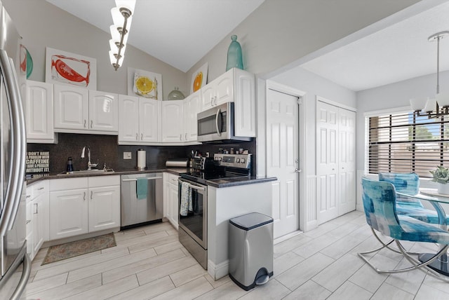 kitchen with lofted ceiling, decorative backsplash, sink, white cabinets, and appliances with stainless steel finishes