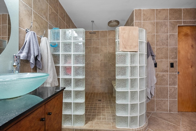 bathroom featuring tile walls, vanity, a tile shower, and tile patterned flooring