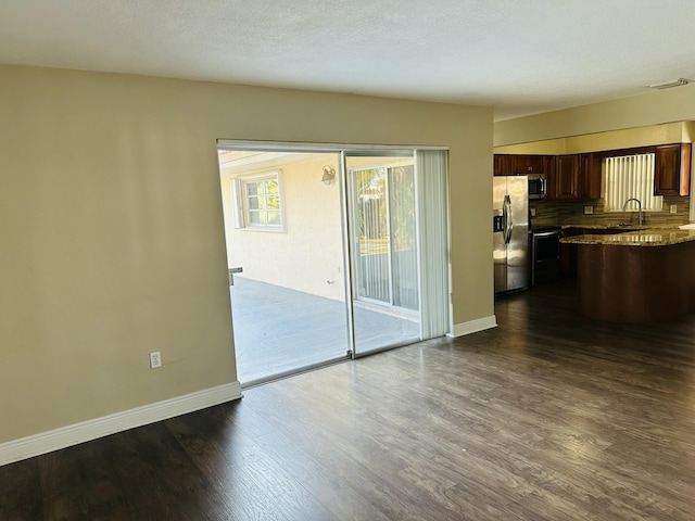 kitchen featuring dark wood-style floors, appliances with stainless steel finishes, a sink, and baseboards