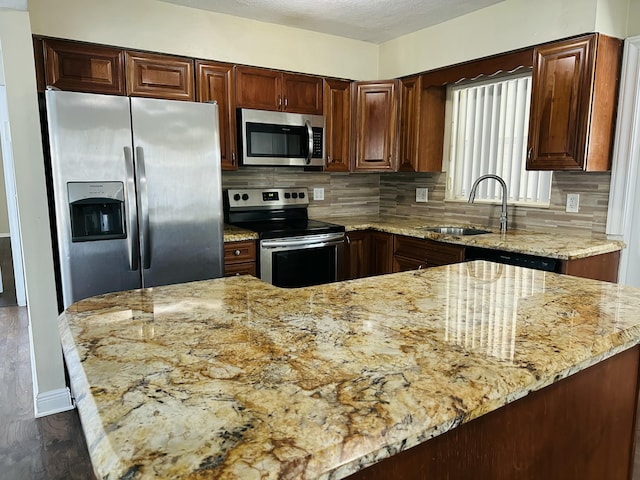 kitchen featuring a sink, appliances with stainless steel finishes, light stone countertops, dark wood-style floors, and tasteful backsplash