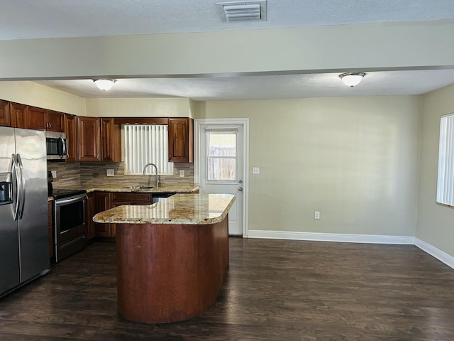 kitchen featuring light stone counters, stainless steel appliances, visible vents, decorative backsplash, and dark wood-type flooring