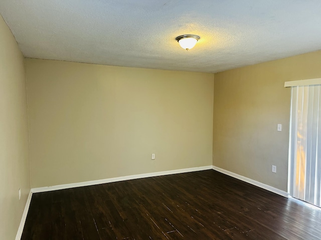 unfurnished room featuring a textured ceiling, dark wood finished floors, and baseboards