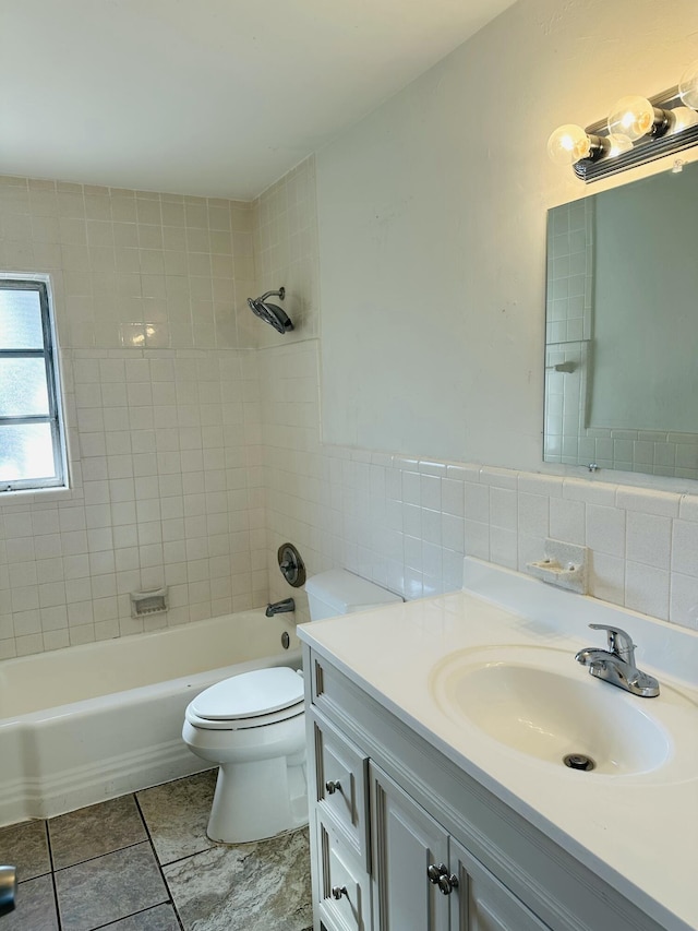 full bath featuring shower / washtub combination, tile walls, toilet, wainscoting, and vanity