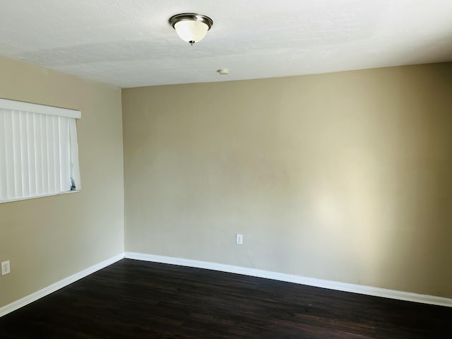 empty room with dark wood-type flooring and baseboards