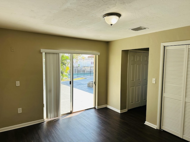 interior space with dark wood-style floors, baseboards, visible vents, and a textured ceiling