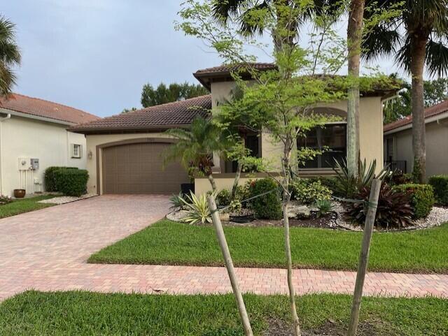 mediterranean / spanish-style home featuring a garage and a front lawn