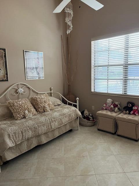 tiled bedroom featuring multiple windows and ceiling fan