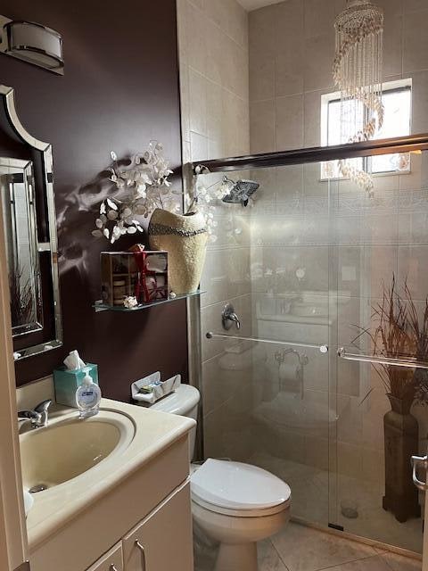 bathroom featuring tile patterned flooring, vanity, toilet, and walk in shower