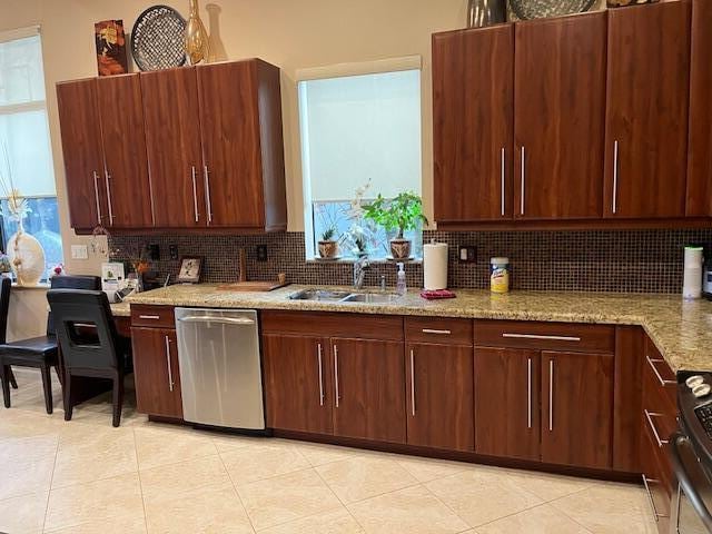 kitchen with stainless steel appliances, light stone counters, tasteful backsplash, and sink