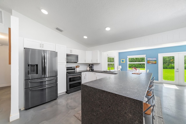 kitchen with appliances with stainless steel finishes, white cabinetry, and vaulted ceiling