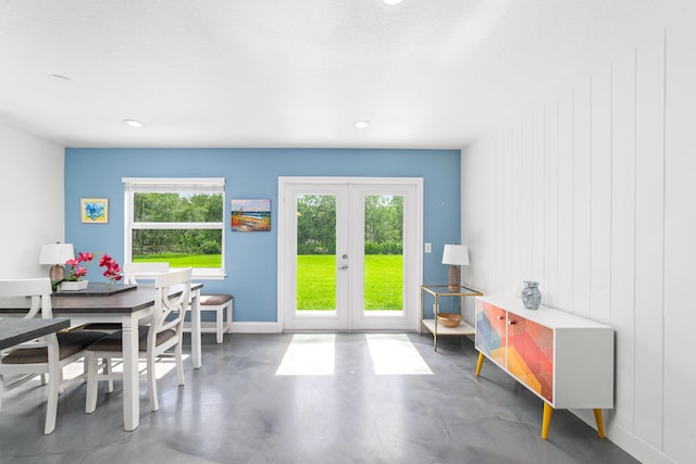 dining room with french doors, a healthy amount of sunlight, a textured ceiling, and concrete flooring