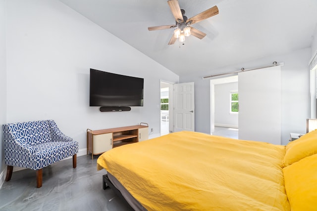 bedroom with ceiling fan, vaulted ceiling, a barn door, and concrete flooring