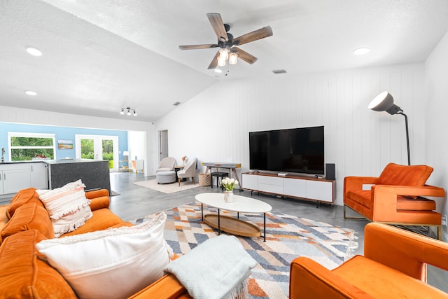 living room with lofted ceiling, a textured ceiling, and ceiling fan