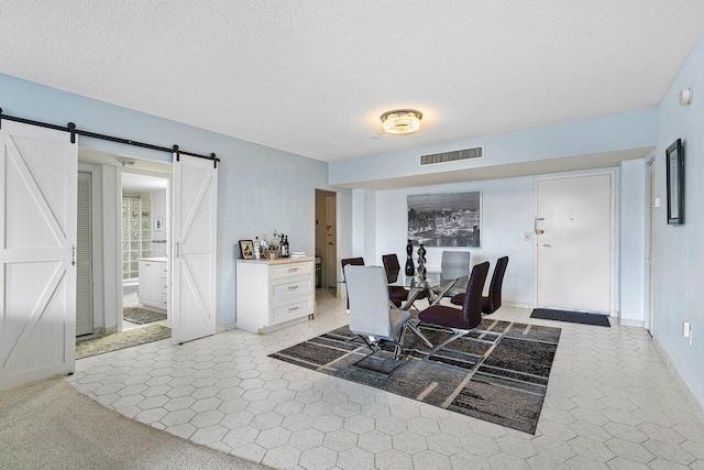 carpeted dining area featuring a textured ceiling and a barn door