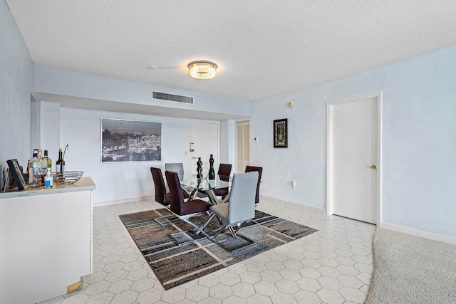 dining area with carpet and a textured ceiling