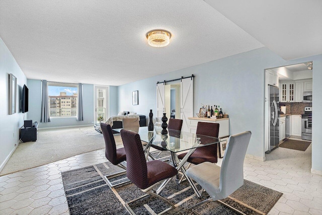 carpeted dining area with a textured ceiling and a barn door