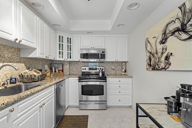 kitchen with decorative backsplash, light stone counters, white cabinetry, sink, and stainless steel appliances