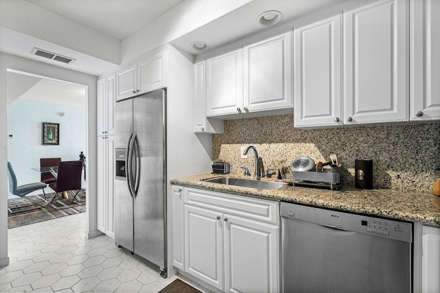 kitchen with tasteful backsplash, sink, white cabinetry, stainless steel appliances, and light tile patterned floors