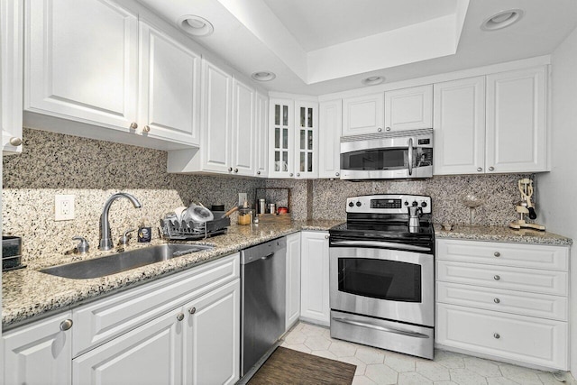 kitchen with decorative backsplash, white cabinetry, light stone countertops, sink, and stainless steel appliances