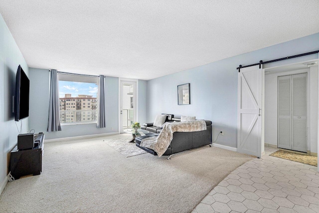 carpeted bedroom with a closet, a textured ceiling, and a barn door