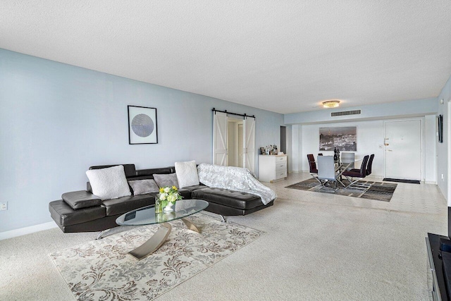 carpeted living room featuring a textured ceiling and a barn door