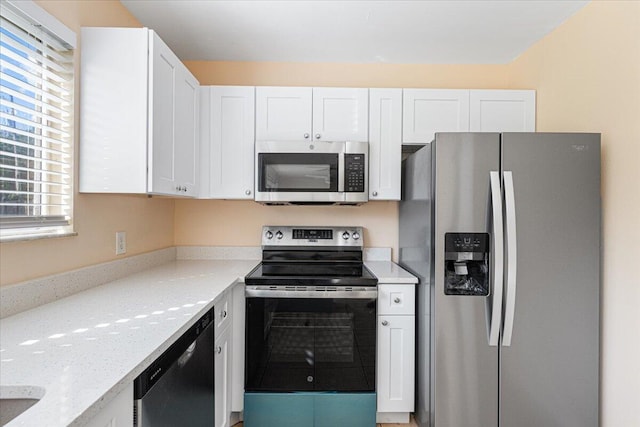 kitchen featuring white cabinetry, light stone counters, a healthy amount of sunlight, and appliances with stainless steel finishes