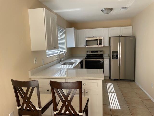 kitchen with stainless steel appliances, sink, kitchen peninsula, and white cabinets