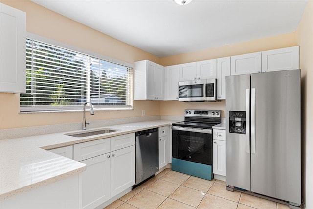 kitchen featuring appliances with stainless steel finishes, white cabinets, sink, and light tile patterned floors