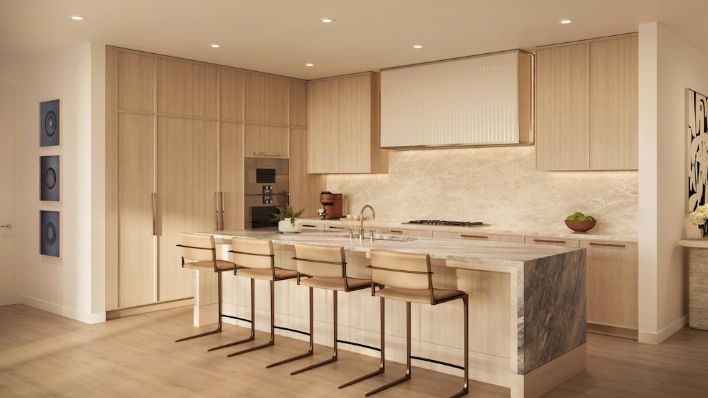 kitchen featuring sink, light brown cabinets, light hardwood / wood-style flooring, backsplash, and a kitchen island with sink