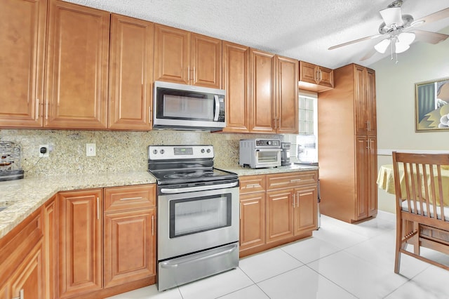 kitchen featuring tasteful backsplash, light stone counters, stainless steel appliances, and light tile patterned floors